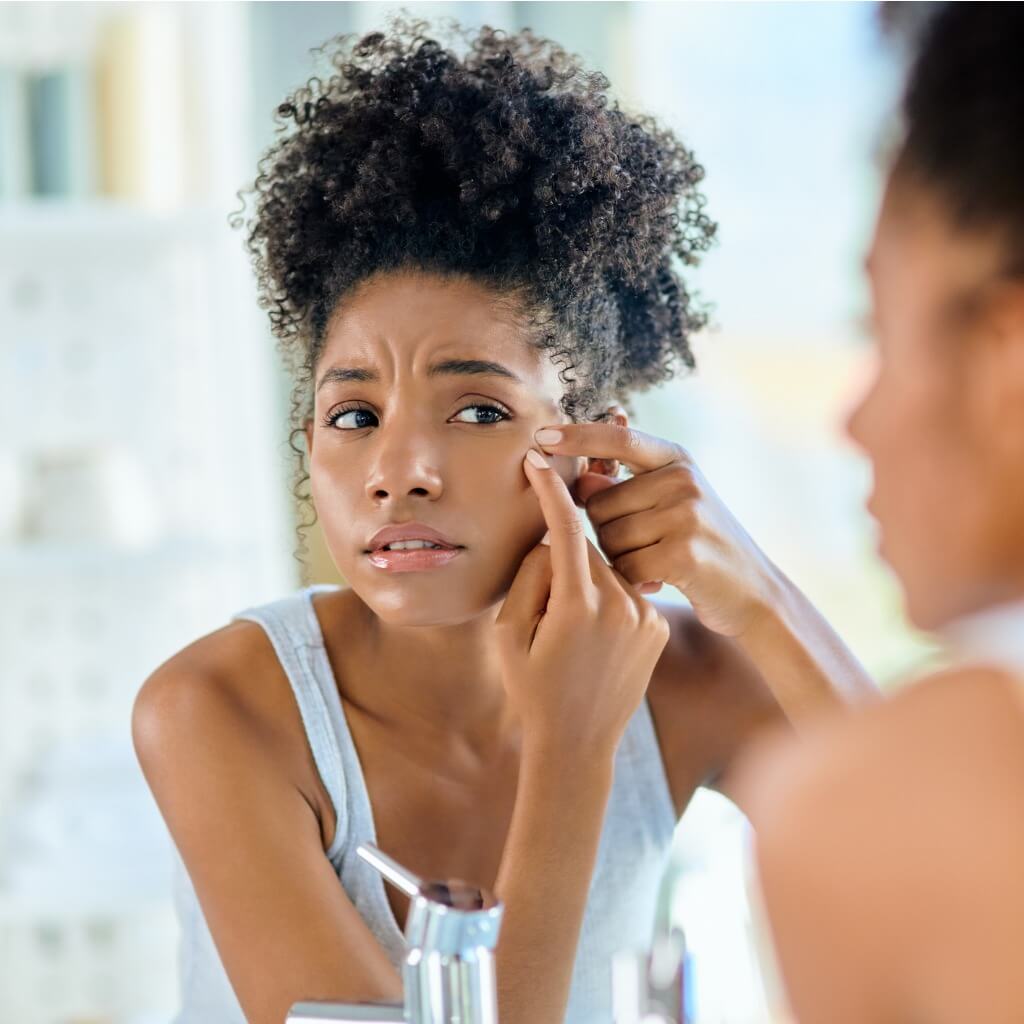 Woman Checking For Acne Using Mirror